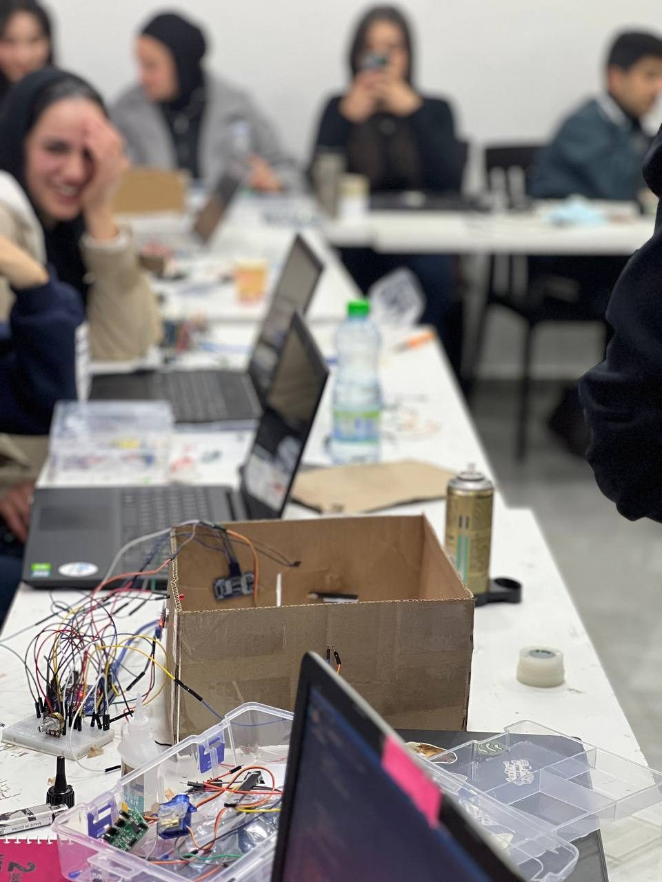 MCC students wiring a robot chassis with breadboards and laptops during a hands-on course
